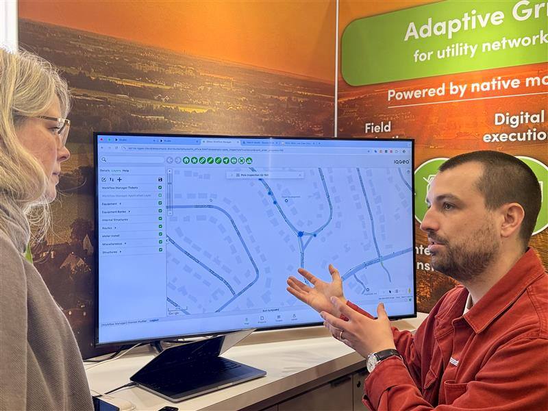 Nahaufnahme eines Messestandes auf der DISTRIBUTECH 2025 mit der IQGeo-Software auf dem Bildschirm